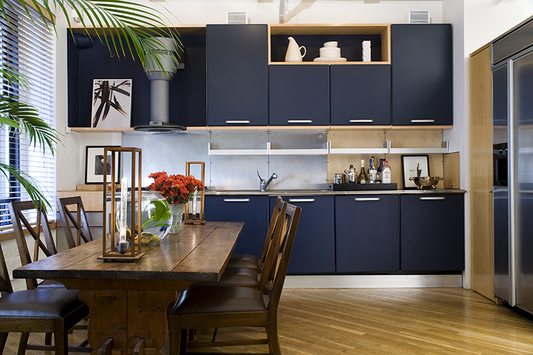 Modern meets retro in biomorphic American Modern dishes by Russel Wright. Contemporary blue kitchen cabinets lend vibrant color.